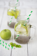 Apple green sliced with chia seeds in glass and fresh apples on the wooden table, Drink to good health
