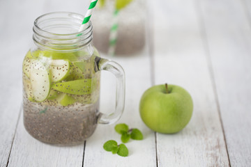 Apple green sliced with chia seeds in glass and fresh apples on the wooden table, Drink to good health