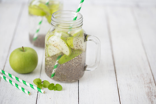 Apple green sliced with chia seeds in glass and fresh apples on the wooden table, Drink to good health