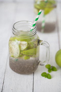 Apple green sliced with chia seeds in glass and fresh apples on the wooden table, Drink to good health