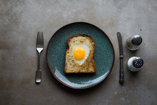 Overhead view of fried egg and toast in a heart shape
