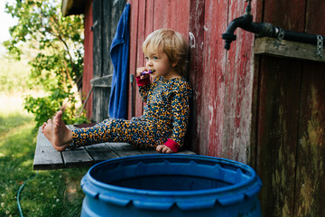 Toddler girl brushes her teeth outside in rural Finland