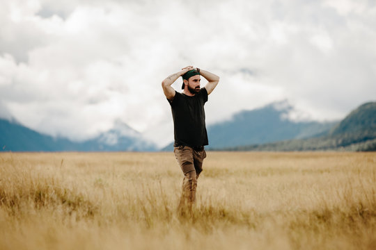 A weary man stands alone in the middle of a New Zealand meadow 