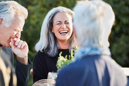 Portrait of senior woman with group of friends enjoying a Farm To Table Dinner Party in backyard