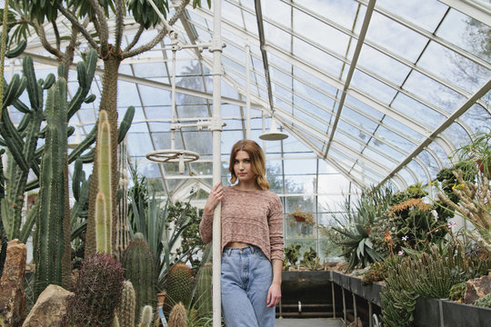 Young woman stands in conservatory