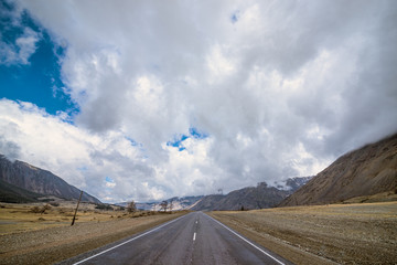panoramic view of plain with road at root of mountains