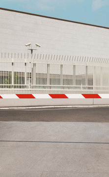 White building with cctv security cameras observing in back of barrier/car stop ramp pulled down