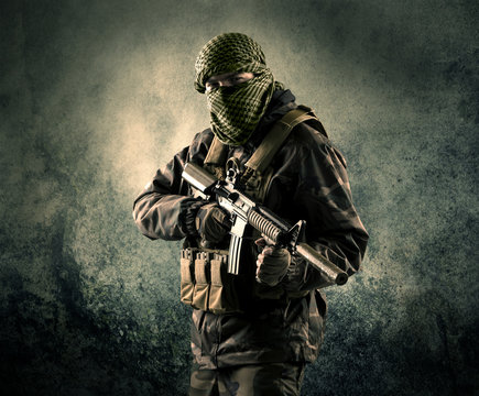 Portrait of a heavily armed masked soldier with grungy background