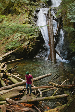 Young man standing next to waterfall