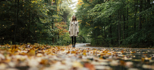 Beautiful blonde girl stands on a wet road in fall 