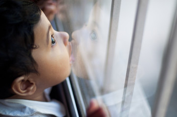 Cute baby girl kissing glass window pane