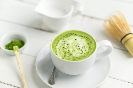 Cup of matcha green tea latte with accessories. This latte is a delicious way to enjoy the energy boost & healthy benefits of matcha. Matcha is a powder of green tea leaves packed with antioxidants.