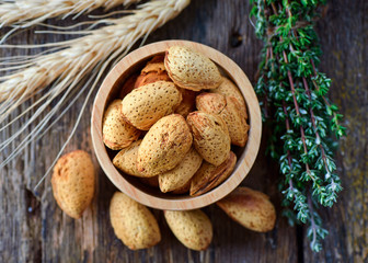Almonds in brown bowl on wooden background