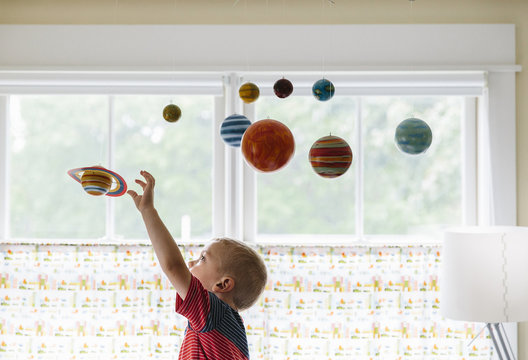 Child Playing with Solar System Mobile