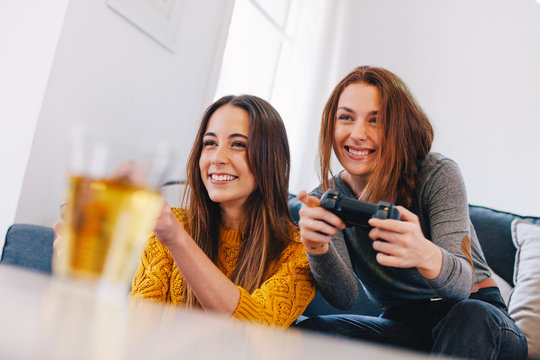 Two happy young female playing video games at home