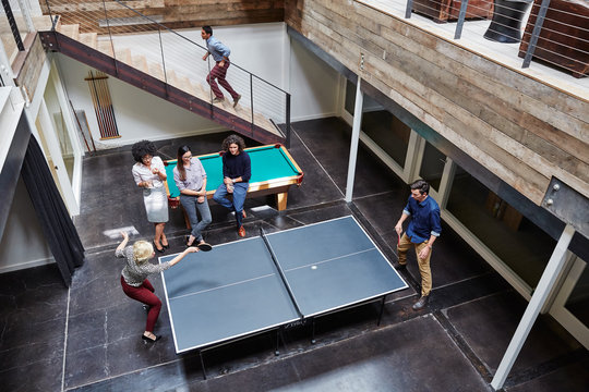 Group portrait of millennials playing ping pong at work