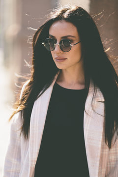 portrait of trendy woman with round sunglasses on the street 