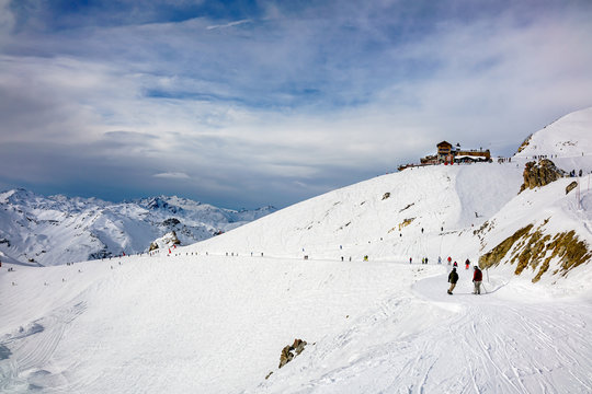 Skiers and snowboarders on the top station slope in Courchevel winter resort, France.