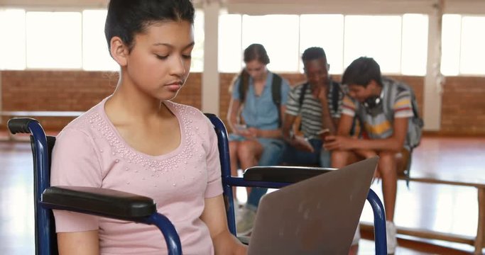 Disabled schoolgirl using digital tablet with classmates in background