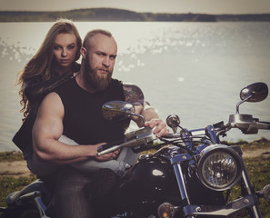 Two people and bike - young woman and bearded man on the motorbike. Adventure and vacations concept. VIntage toned image.