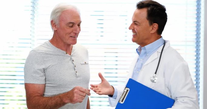 Doctor and senior man smiling while having discussion over a report