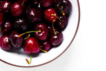 Cherry with water drops in a white-brown bowl on a white background, natural light