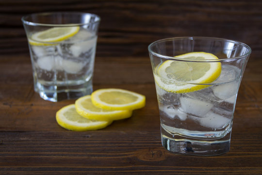 Ice refreshing drink with lemon on a brown wooden background