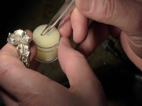 Jeweler is inserting and fixing a gem on a ring.