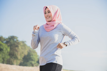 healthy sporty woman wearing hijab smiling while jogging