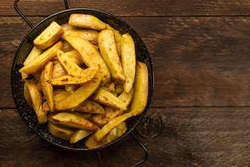 Crunchy roasted potatoes in skillet on dark rustic texture