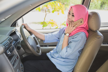 beautiful woman wearing hijab talking on the phone while driving