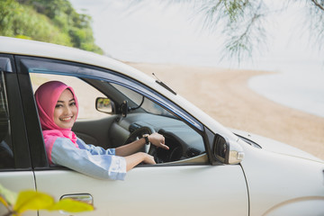 happy woman wearing hijab travelling with a car to the beach on