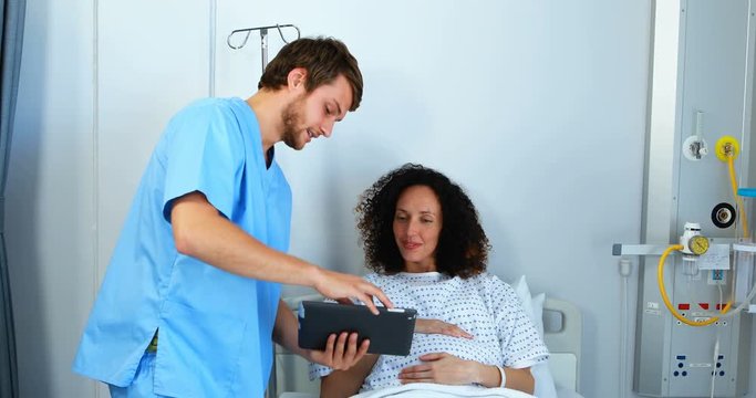 Doctor showing medical report to pregnant woman on digital tablet