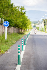 bicycle lane with green pole and road sign