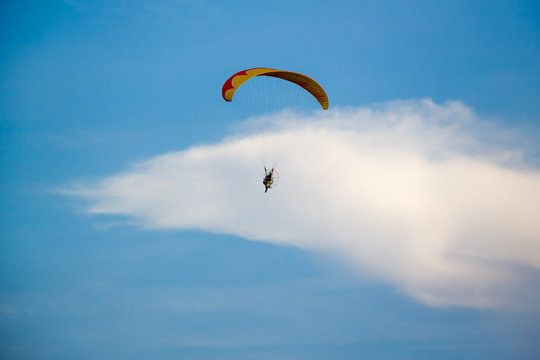 man flying with paramotor engine glider parachute on beautiful blue sky
