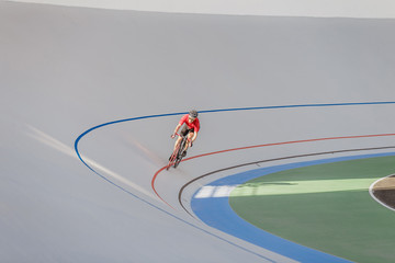 Bicyclist on cycle track outdoor. Active man racing at white velodrome.