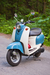 Blue retro scooter in the forest with helmet