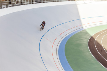 Bicyclist on cycle track outdoor. Active man racing at white velodrome.