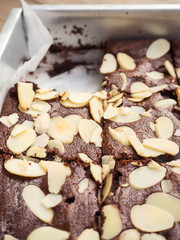 Homemade brownies in baking tray. Topping with almond sliced.