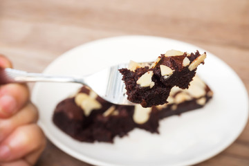 Woman hand holding fork picking sliced homemade brownies.