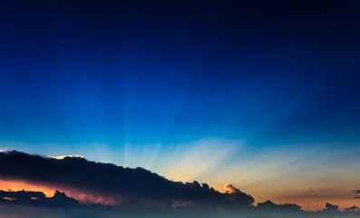 Incredibly, awesome bright, colorful sunset rays become outside a clouds front against the background clear blue sky. Natural phenomenon.