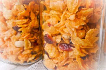 Corn flakes with honey and dried raisin, healthy snack in glass jar.