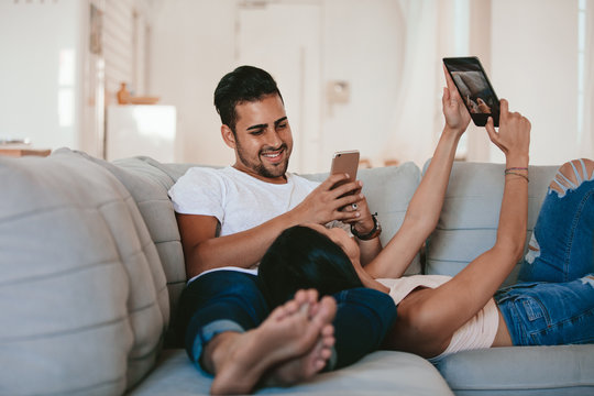 Young couple relaxing at home with their digital devices