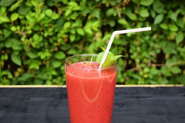 glass of strawberries, peach smoothie with straw on wooden table. Protein cocktail. Healthy drink. Fresh homemade smoothie. Healthy breakfast of smoothie,