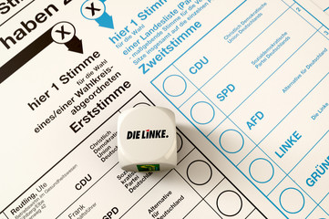 Stimmzettel zur Bundestagswahl, auf dem 1 W&uuml;rfel liegt, der Wurf ergab Die Linke