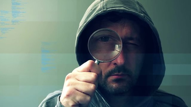 Computer hacker with magnifying glass, spyware and ransomware concept