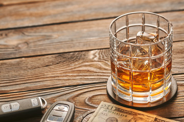 Glass of whiskey or alcohol drink with ice cubes and car key. Drink and drive concept.