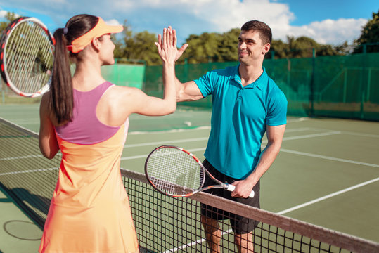 Happy couple with rackets on outdoor tennis court