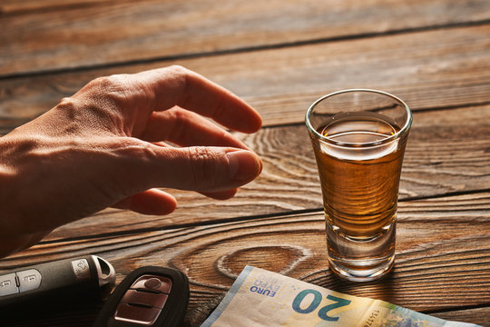 Man's hand reaching to glass with alcohol drink and car key. Drink and drive concept.