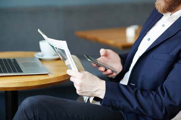 Employer with newspaper and smartphone messaging at break